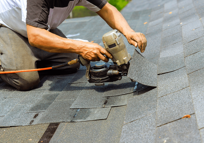 Worker using nail gun on roof