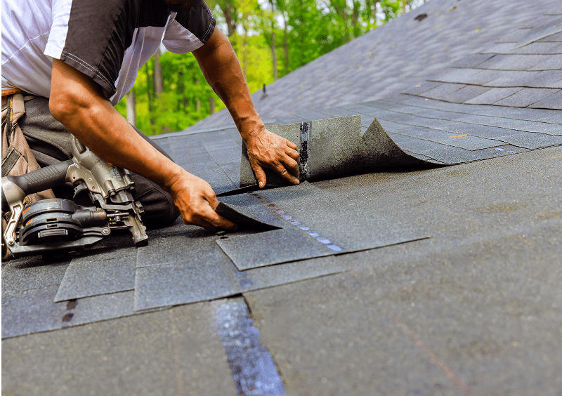 Worker laying roof shingles