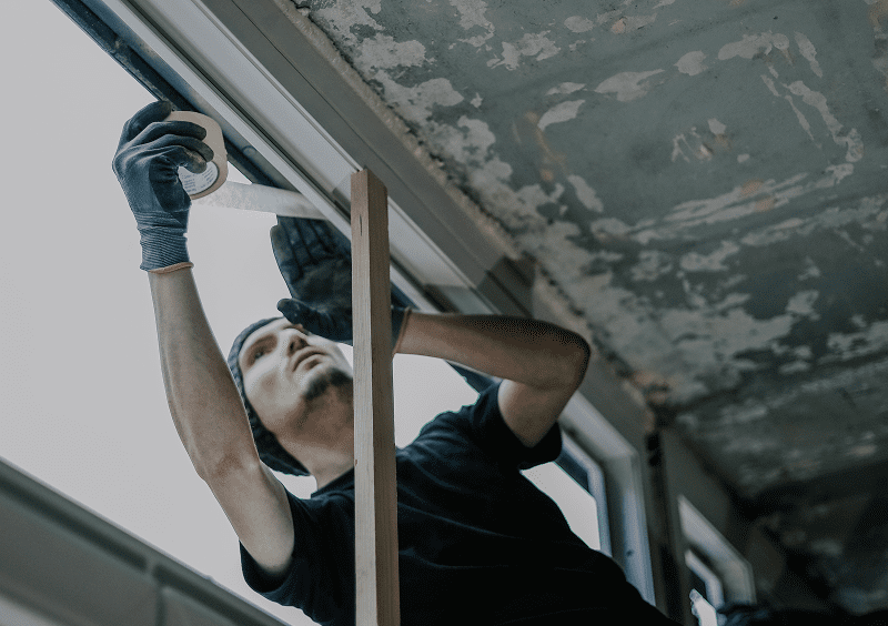 Man repairing window with adhesive tape