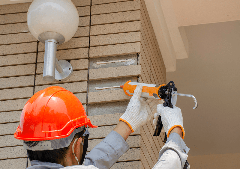 Construction worker sealing wall joints