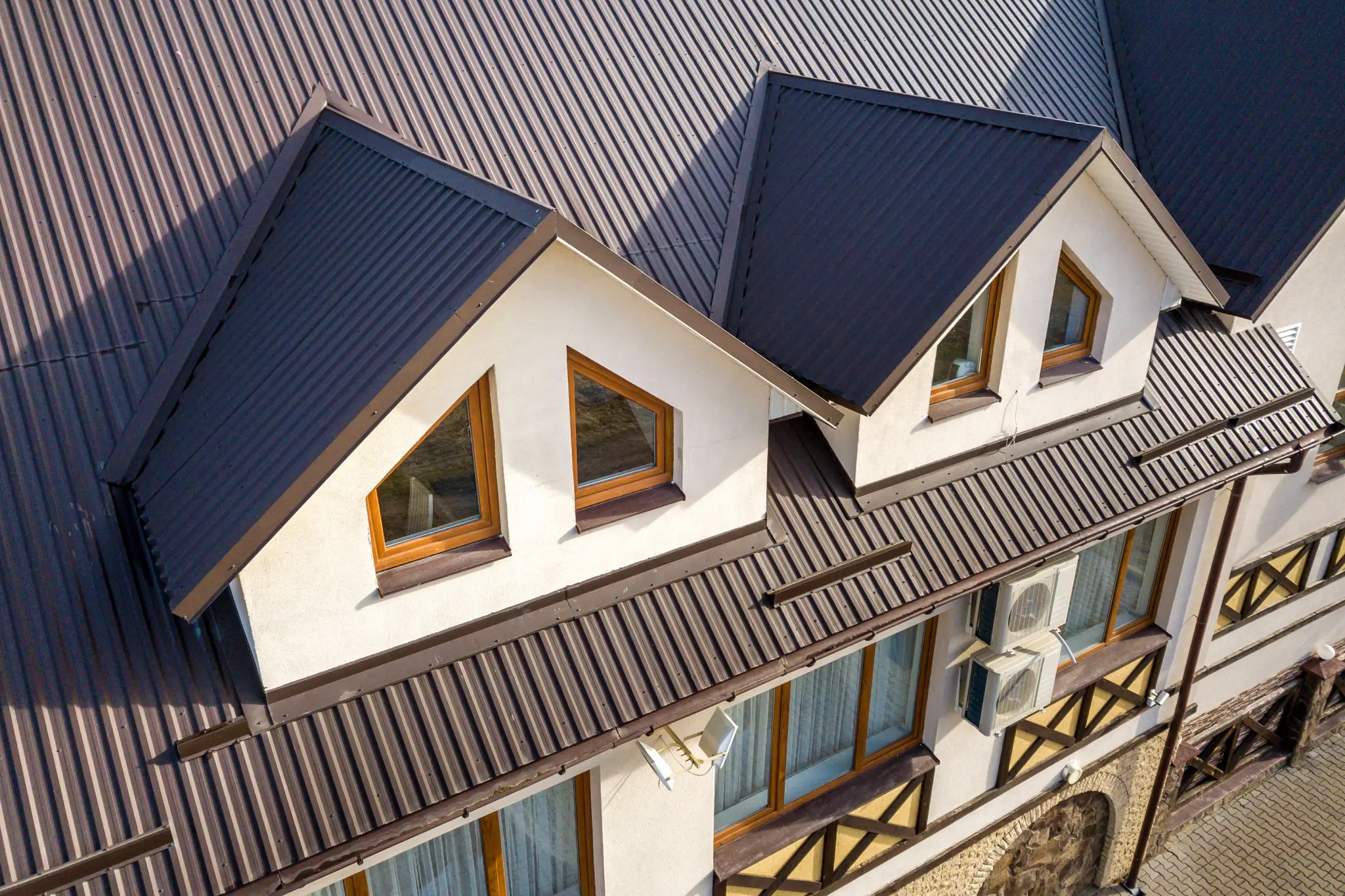 Modern house roof with triangular dormer windows and metal roofing.