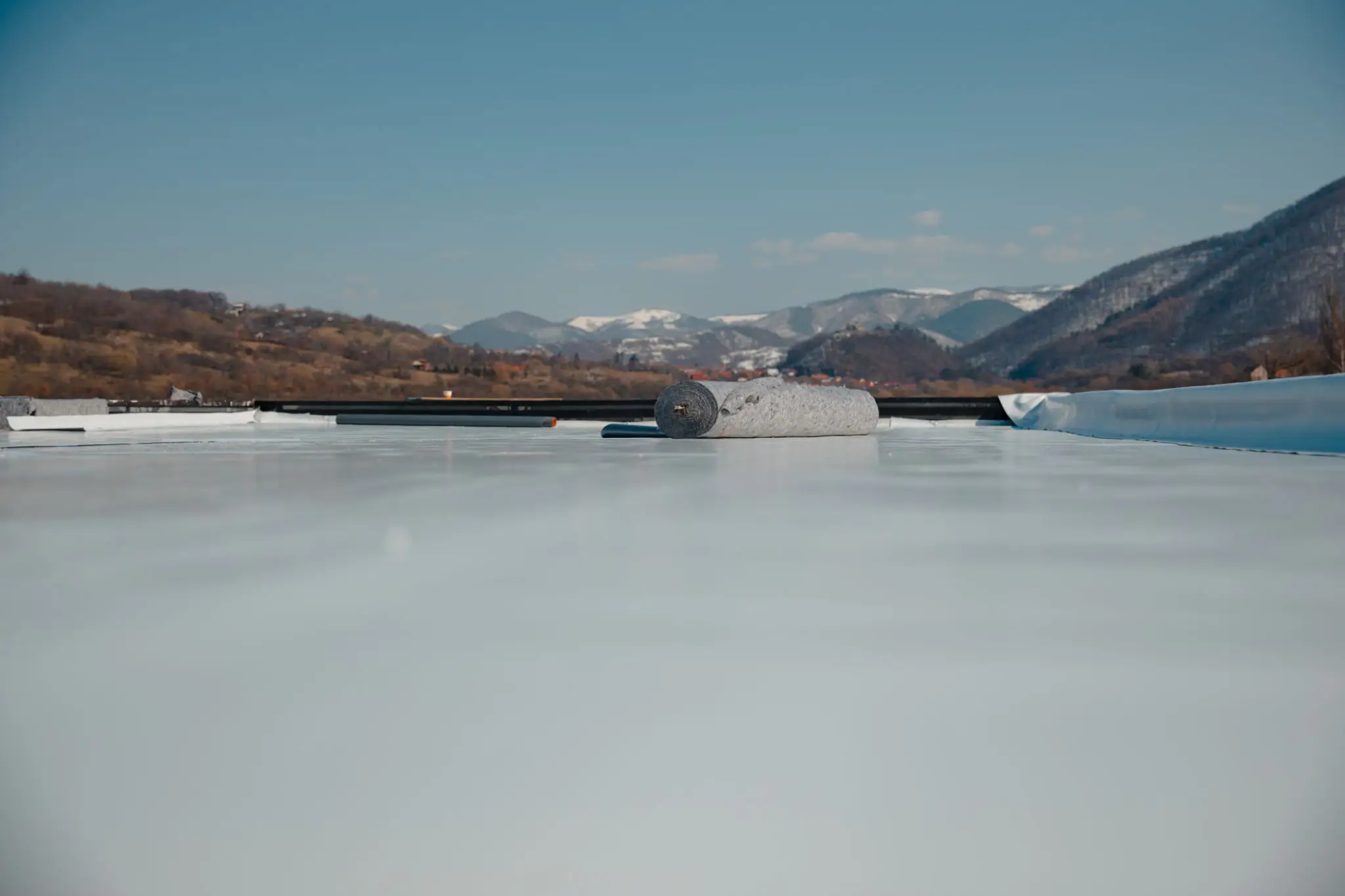 Frozen lake with mountains in the background under a clear sky.