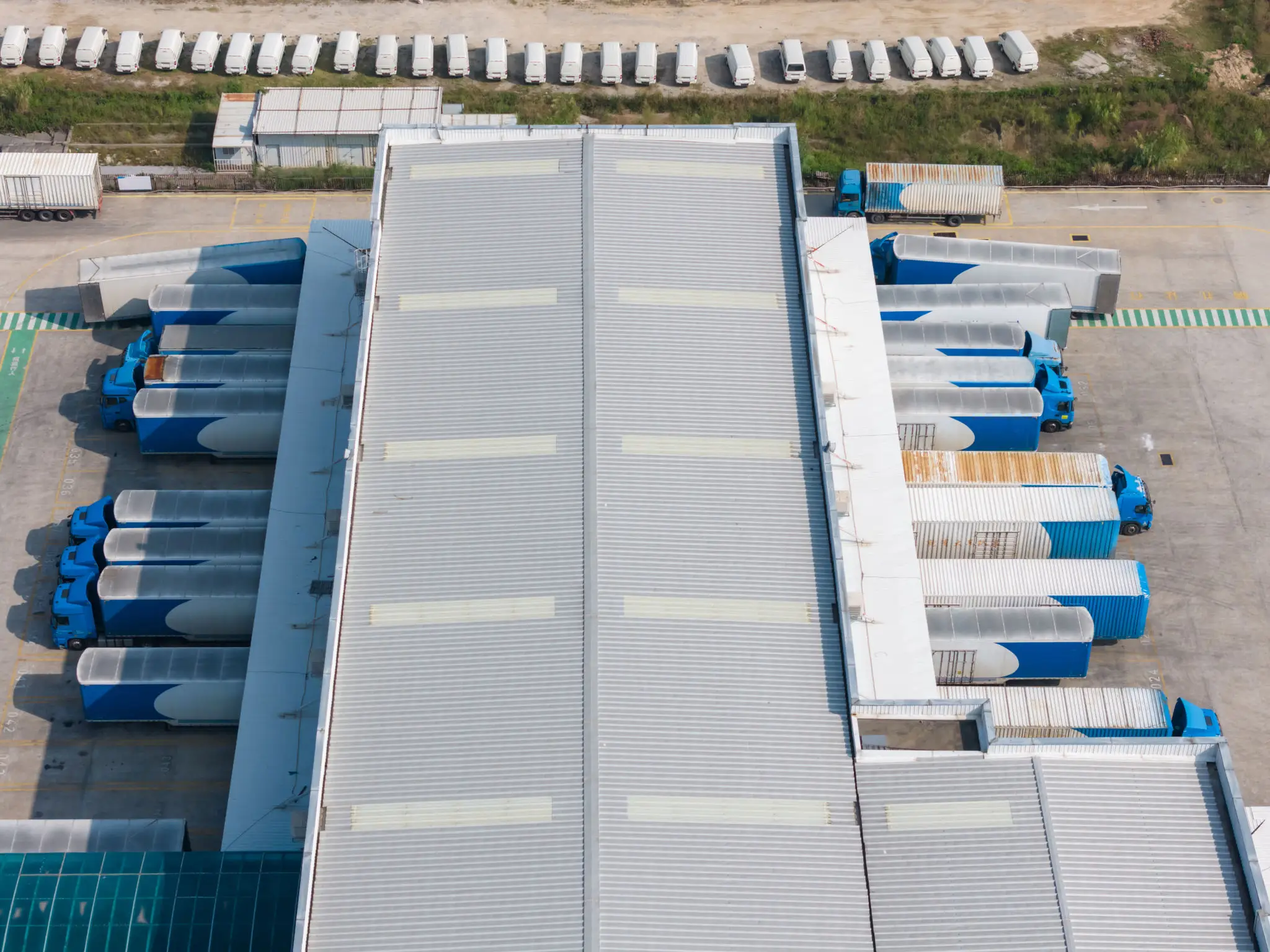 Aerial view of a large industrial warehouse with trucks parked alongside.