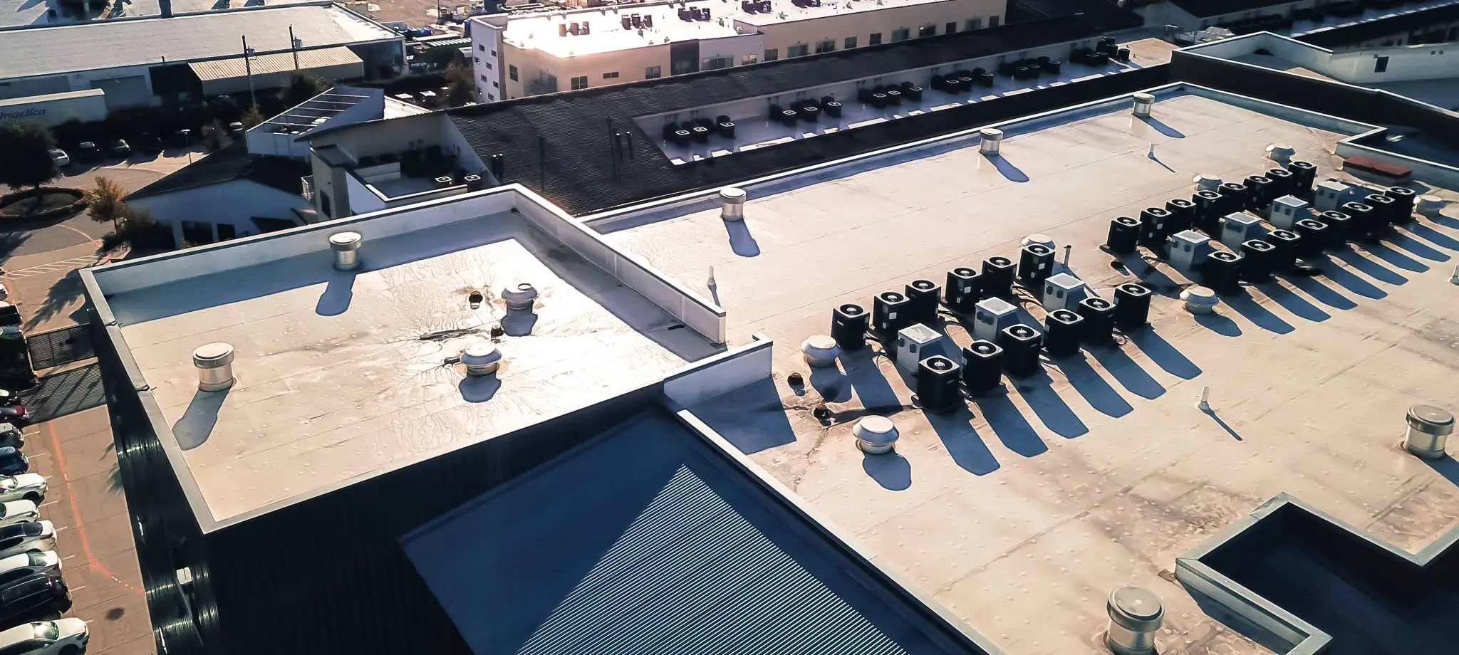 A rooftop with various HVAC units and vents under clear daylight.