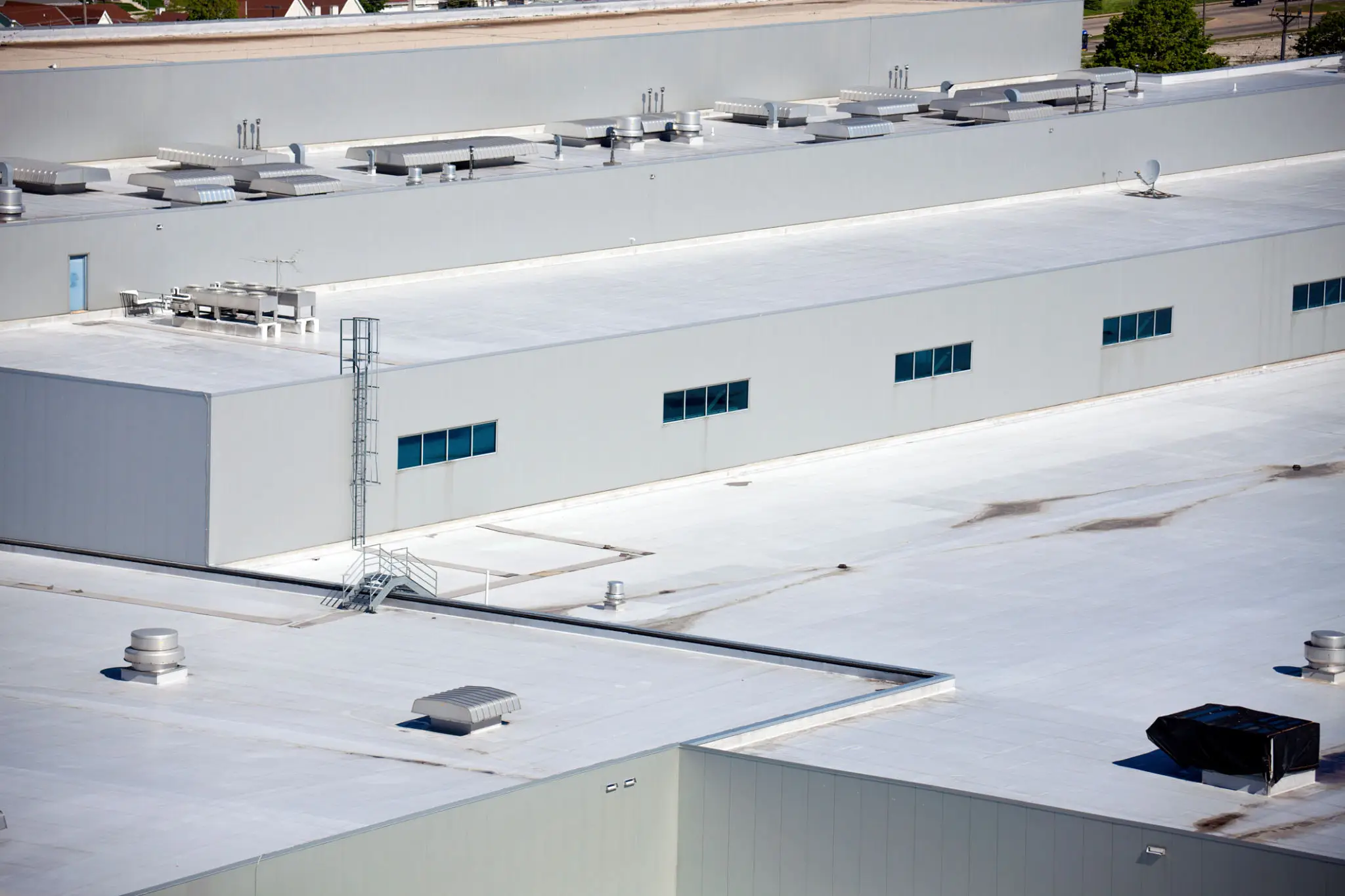 A large white industrial rooftop with HVAC units and small windows.
